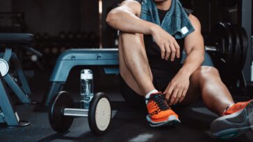A person wearing gym clothes and sneakers working out with gym weights in a gym.